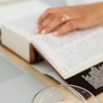 Dictionary Technology - Woman Sitting at the Desk with a Laptop and a Cup of Coffee while Using a Paper Dictionary