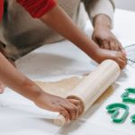 Cooling Overclocking - Crop focused African American child rolling out dough near parent while preparing gingerbread cookies at home