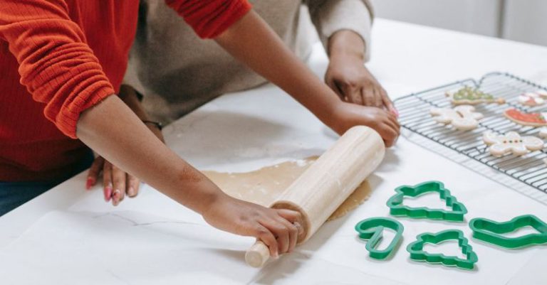 Cooling Overclocking - Crop focused African American child rolling out dough near parent while preparing gingerbread cookies at home