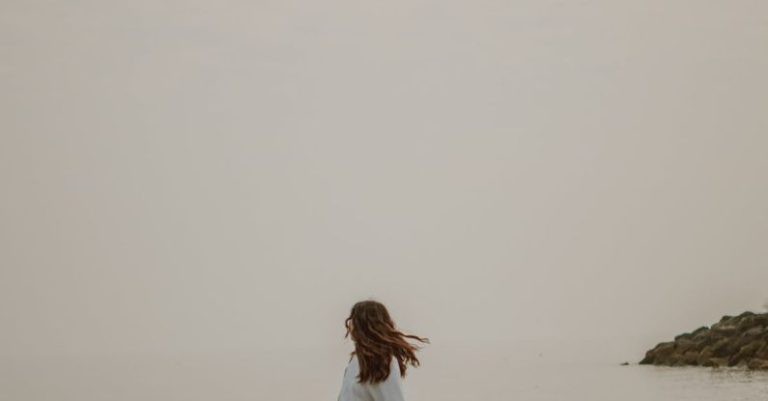 Dual Boot - Anonymous tourist admiring sea from stone in misty weather