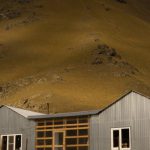 Silent Build - Picturesque view of small rural cottage on grassy terrain near hills under cloudy sky