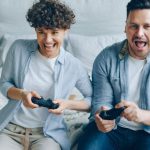 Mini-ITX Gaming - A Couple Sitting on a Bed and Playing a Video Game