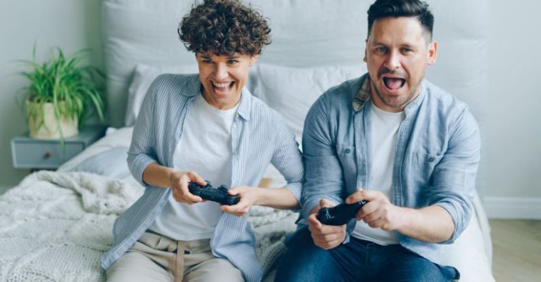 Mini-ITX Gaming - A Couple Sitting on a Bed and Playing a Video Game