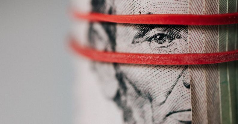 Upgrade Budget - Closeup of rolled United States five dollar bills tightened with red rubber band