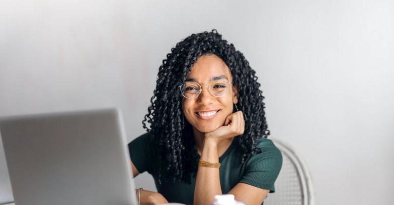 Content Creation Budget - Happy ethnic woman sitting at table with laptop