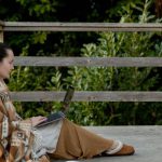 Sleeper PC - Adult focused female blogger sitting on veranda with laptop